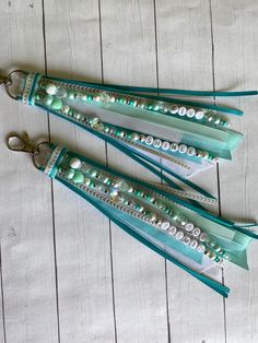 three green and white beaded lanyards sitting on top of a wooden table