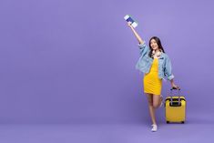 a woman in a yellow dress is holding a piece of luggage and pointing to the side