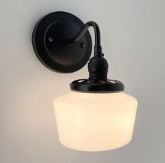 a black wall light with a white glass shade on it's face and arm