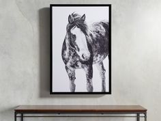 a black and white photo of a horse on a wall above a table with a shelf