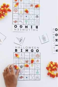 a child's hand is playing with candy corn on a halloween themed board game