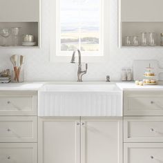 a white kitchen sink sitting under a window next to a counter top with dishes on it