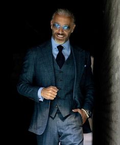 This New York cut three-piece suit stars in a Metropolitan blue with subtle textured plaid. Tailored... Blue Suit Style, James Bond Suit, Christopher Korey, Mens Tailored Suits, Red Overcoat, Windowpane Suit, Flannel Suit, Yellow Suit, Classy Suits