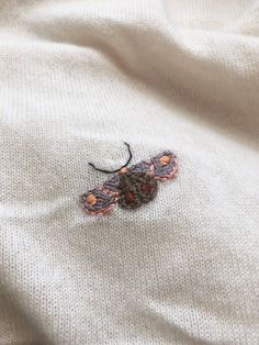 an embroidered butterfly on a white sweater