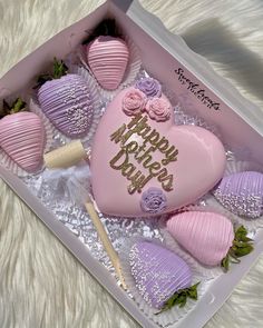 a pink heart shaped cake in a box with purple frosting and strawberries on it