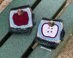 two crocheted apples sitting on top of a green bench