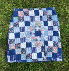 a blue and white patchwork quilt laying on the grass