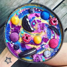 a person's hand holding a bowl with colorful food on it