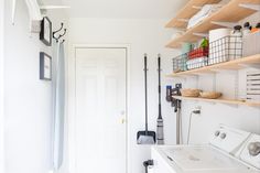 a washer and dryer in a room with shelves above the door that are filled with items