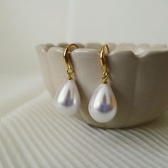 "Free shipping on orders over $35.00  [North America ONLY].  The 14K-Gold-Plated Water Drop Pearl Dangle Earrings are a stunning and timeless accessory that will add elegance to any outfit. The earrings feature a water drop shaped design plated with 14K gold that glistens beautifully in the light. Suspended from the gold plating is a luxurious, white imitation pearl that adds a touch of sophistication to the earrings. The earrings dangle delicately from the ear, making them the perfect addition to any special occasion or everyday look. The 14K-Gold-Plated Water Drop Pearl Dangle Earrings are versatile, lightweight, and easy to wear, making them an ideal choice for any jewelry collection. With their classic design and exquisite materials, these earrings are sure to become a staple piece in Pearl Dangle Earrings, Pearl Earrings Dangle, Timeless Accessories, Etsy Earrings Dangle, Water Drop, Earrings Dangle, Staple Pieces, Shape Design, Gold Plating