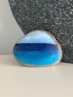 a blue and white rock sitting on top of a table next to a black vase