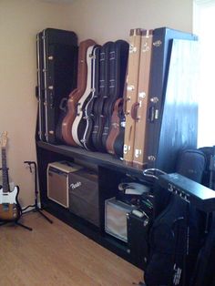 guitars and amps are lined up on a shelf in a room with hard wood floors