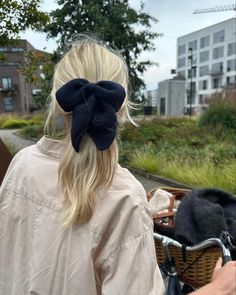 a woman riding a bike down a street with a bow in her hair