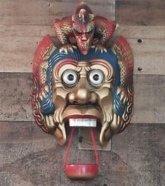 a mask hanging on the side of a building with its mouth open and tongue out