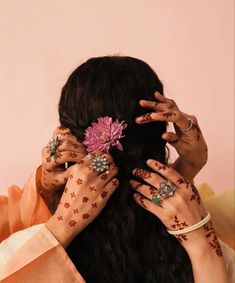 a woman with her hands on her head holding a flower