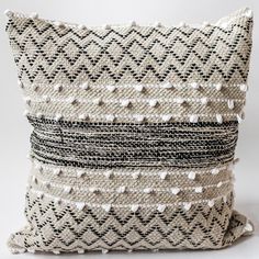 a black and white pillow with tassels on it