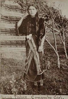 an old black and white photo of a woman in native clothing holding a whip stick