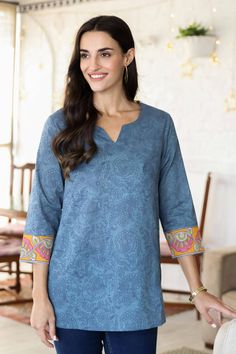 A lovely paisley pattern swirls across this cadet blue tunic designed by India's Isha Jain. Crafted from 100% cotton, the tunic features a screen-printed paisley motif and a block-printed floral pattern on contrasting marigold cuffs. Lateral slits let you slip the tunic over your head without fumbling with buttons or zippers. Blue Cotton Tops With Paisley Print, Printed Cotton Tops With Split Neck, Cotton Printed Top With Split Neck, Cotton Printed Split Neck Tops, Cotton Split Neck Printed Tops, Blue Cotton Straight Kurta Tops, Blue Cotton Tops With Printed Motifs, Blue Cotton V-neck Tunic, Blue Block Print Straight Kurta Top