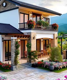 a house with flowers on the balcony and landscaping around it, in front of mountains