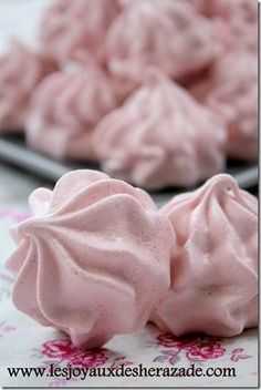 pink meringue on a plate next to another serving platter full of mering