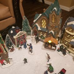 a table topped with lots of christmas figurines on top of snow covered ground