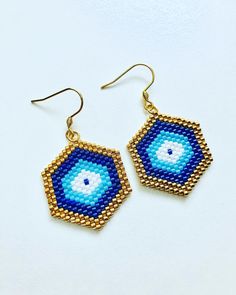 blue and gold beaded earrings with an evil eye in the center on a white background