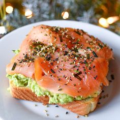 a piece of bread with salmon and avocado on it sitting on a plate