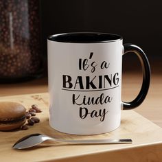 a black and white coffee mug sitting on top of a wooden table next to a spoon