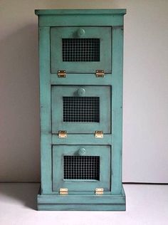 a small blue cabinet with three doors and two drawers on the bottom, sitting against a white wall