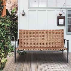 a wooden bench sitting on top of a wooden floor next to a white wall and green plants