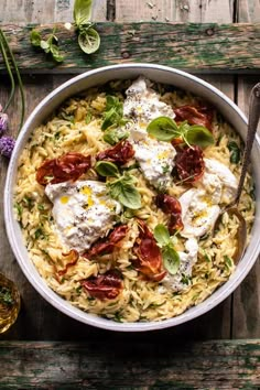 a white bowl filled with pasta and cheese on top of a wooden table next to flowers