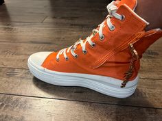 Introducing our Orange High-Top Sneakers – a vibrant and stylish addition to your footwear collection. These sneakers combine bold color and contemporary design to make a statement wherever you go. The striking orange hue exudes confidence and energy decorated with gold charms, while the high-top style adds a touch of urban flair. Whether you're stepping out for a casual day or looking for a unique accent to your outfit, our Orange High-Top Sneakers are the perfect choice. Elevate your style and Orange Sneakers, Gold Charms, Zipper Boots, Footwear Collection, Comfortable Sneakers, Stepping Out, Bold Color, Elevate Your Style, Gold Charm