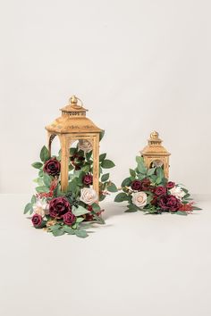 two gold lanterns with red and white flowers on them are sitting next to each other