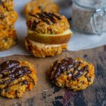 carrot cookies with chocolate drizzled on top and an apple in the background