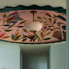 a ceiling light hanging from the side of a room with painted flowers and birds on it