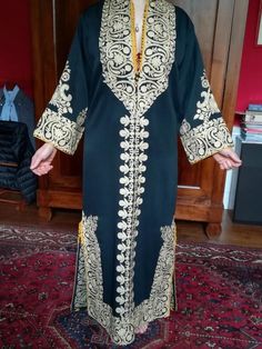 This is a handmade Syrian Aghabani dress, featuring intricate gold embroidery on rich black fabric. The design showcases traditional motifs, with detailed patterns along the sleeves, neckline, and hem, making it a stunning example of Syrian craftsmanship. Perfect for special occasions, the luxurious embroidery elevates its elegance and cultural significance. Measurements: - Armpit to armpit: 60 cm - Length: 135cm A beautiful piece that showcases the artistry and tradition of Syrian craftsmanship Ceremonial Long Sleeve Dress With Resham Embroidery, Traditional Long Sleeve Dress With Intricate Embroidery, Gold Embroidered Dresses For Traditional Ceremonies And Festivals, Elegant Festive Embroidered Dress With Traditional Patterns, Ceremonial Long Sleeve Dress With Zari Work, Traditional Dresses With Gold Embroidery For Ceremonies, Eid Dress With Gold Embroidery In Traditional Drape, Multicolor Embroidered Long Sleeve Dress With Zari Work, Eid Dress With Gold Embroidery And Traditional Drape