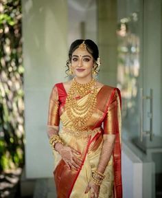 a woman in a yellow and red sari with gold jewelry on her neck, standing outside