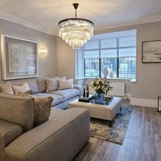 a living room filled with furniture and a chandelier hanging over the top of it