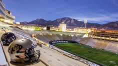 an empty football stadium with helmets on the sidelines and mountains in the background at night