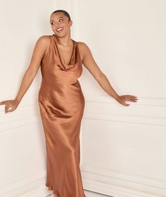 a woman in a brown dress posing for the camera with her arms outstretched and hands out