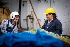 two men in hard hats are smiling at each other