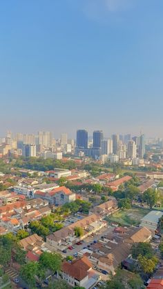 an aerial view of a city with tall buildings and lots of trees in the foreground