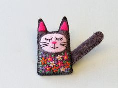 This sleepy kitty with colourful flower embroidery detail is a whimsical brooch pin.  It is made from 100% black wool felt and is hand-stitched with attention to detail.  The floral embroidered detail consists of the tiniest lazy-daisy stitches and French knots. The cat is 4.5 cm (1 3/4'') tall by 3.5 cm (1 3/8'') wide  [6 cm - 2 3/8'' if you include tail].  This listing is for one felt kitty.  Each cat is made to order, so allow a day or two for me to make it with great care. A great gift for a Sleepy Kitten, Embroidered Cat, Felt Crafts Patterns, Lazy Daisy Stitch, Felt Gifts, Felt Halloween, Unique Brooch, Felt Embroidery, Felt Cat