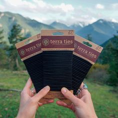 a person holding up a cardboard box in front of the camera with mountains in the background