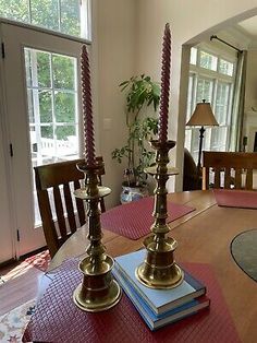 two candles sitting on top of a wooden table next to a window in a living room