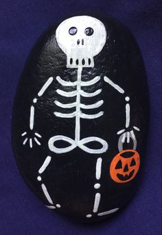 a rock with a skeleton painted on it and a jack - o'- lantern