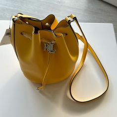 New Ralph Lauren Yellow Leather Bucket Bag Tote Purse. $175. Height: 8.5”. Width: 7.25”. Depth: 5.5”. Ralph Lauren Shoulder Bag With Gold-tone Hardware For Shopping, Yellow Travel Bag With Branded Hardware, Yellow Bucket Bag With Detachable Handle, Luxury Yellow Bags With Silver-tone Hardware, Daily Use Bucket Bag With Silver-tone Hardware, Elegant Yellow Bucket Bag With Top Handle, Elegant Yellow Top Handle Bucket Bag, Ralph Lauren Bag With Gold-tone Hardware For Shopping, Ralph Lauren Shopping Bag With Gold-tone Hardware