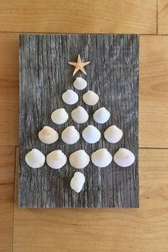 a christmas tree made out of seashells and starfish on a wooden board