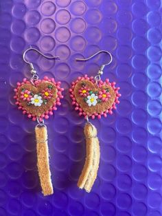 some kind of earrings with beads and flowers on it's ear wires, sitting on a purple surface