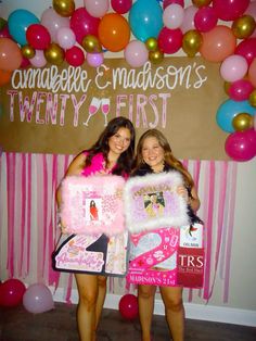 two women standing next to each other in front of balloons